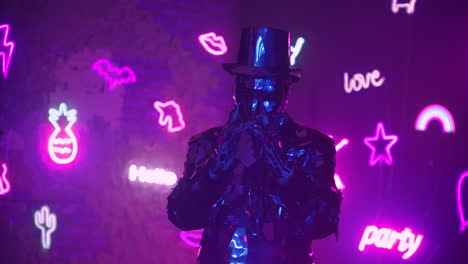 A-man-dances-in-neon-light-in-a-glass-suit.-Shiny-sparkling-silver-suit-and-blue-purple-neon-light.-New-year-party